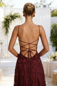 Close-up of elegant wine red lace evening dress featuring a cross strap backless design