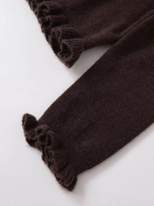 Detailed macro view of dark coffee knit sleeves with elegant ruffled hem texture