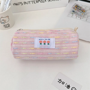 Estuche de tweed rosa con bordado de tulipanes y cremallera metálica en un escritorio