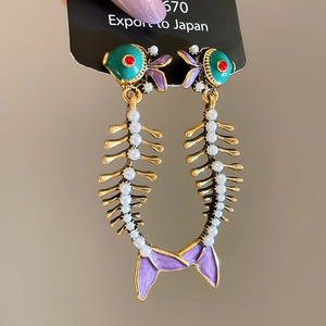 Detailed view of fishbone earrings featuring green enamel and inlaid white pearls