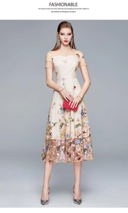 Close-up of intricate multi-color floral embroidery on beige tulle dress mesh sleeve