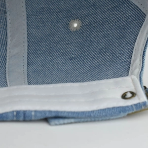 Detail of light blue washed denim hat showing inner lining and metal buckle closure