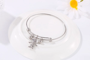 Détail du bracelet en acier titane argenté avec breloque garçon et cloches sur un plateau
