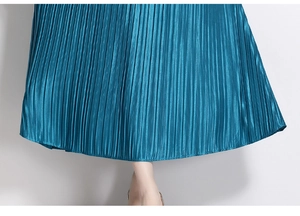 Detailed close-up of pleated peacock blue dress hem with silk-like satin texture