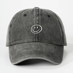 Detail view of washed dark grey denim baseball cap with white embroidered smiley face