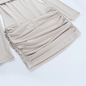 Vue détaillée des fronces latérales et du tissu élastique d'une robe moulante beige