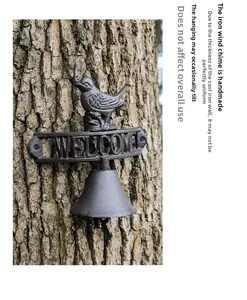Detailed cast iron welcome door bell with bird figurine on a rustic tree bark background