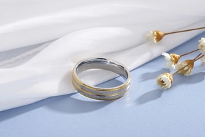 Detail of two-tone matte stainless steel ring with gold edges on elegant silk background