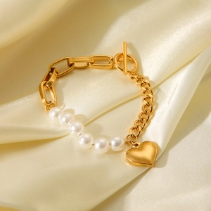 Detail of gold pearl bracelet with heart pendant and OT toggle clasp on silk