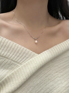 Close-up of a s925 silver knot necklace featuring a round light pink freshwater pearl