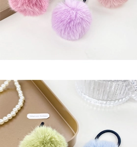 Close-up of colorful plush ball hair ties in pastel pink, purple, green, and blue hues