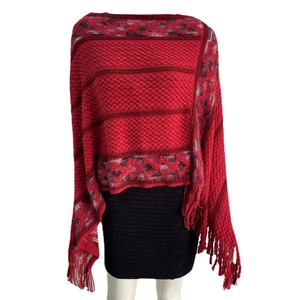 Close-up of red knitted poncho with ethnic diamond patterns and fringe hem detail