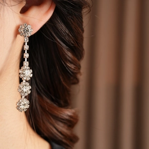 Detail view of silver tassel earrings with floral crystals worn by a model