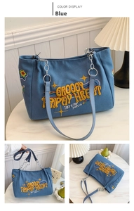 Detail of blue canvas tote bag with colorful embroidery and metal chain shoulder straps