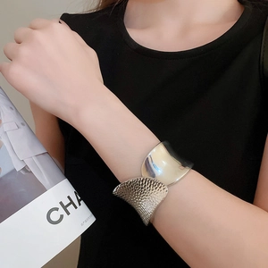 Close-up of model wearing silver irregular hammered wide open bangle with mixed textures