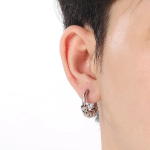 Macro shot of a silver hoop earring with intricate dragon texture on male model