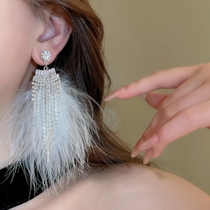 Detail of elegant white feather earrings with sparkling rhinestone fringe on a model