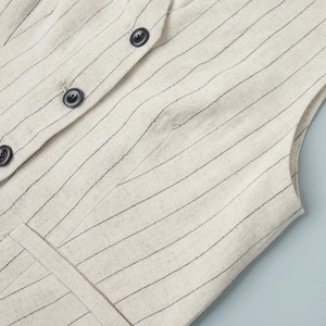 Detail shot of beige pinstripe vest showing cotton linen fabric texture and black buttons