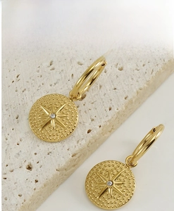 Détail de boucles d'oreilles étoile à huit branches en or 18K avec zircon scintillant