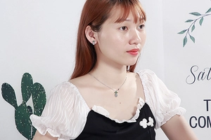 Close-up of a silver strawberry pendant necklace and earrings set worn by a model
