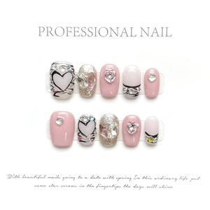 Close-up of pink and silver press-on nails with 3D heart gems and glitter details