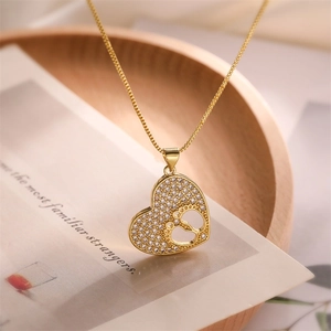 Macro detail of gold plated heart pendant with pavé diamonds and cutout footprint pattern