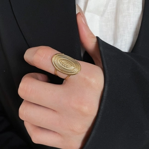 Close-up of golden stainless steel oval ring with elegant concentric wavy textures