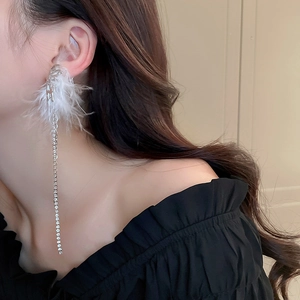 Elegant silver tassel earrings with white feathers and rhinestones on female model