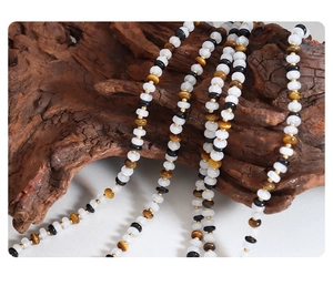 Artistic display of black and white stone beaded choker necklace on natural wood root