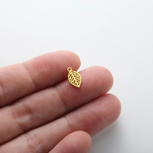 Close-up of a small gold hollow leaf charm for DIY jewelry making held in hand