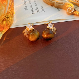Gros plan de boucles d'oreilles étoile en oeil de tigre avec zircon sur cuir brun
