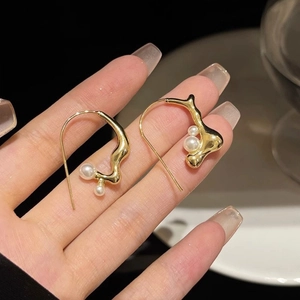 Macro shot of gold irregular geometric pearl earrings with a melted metal texture