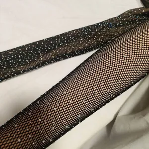 Close-up of black fishnet leggings with sparkling colorful rhinestones and fine mesh detail