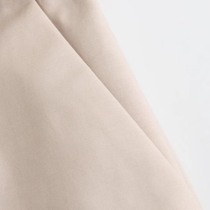 Gros plan sur la texture du tissu tissé kaki clair pour un short plissé décontracté