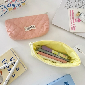 Close-up of quilted macaron colored pencil cases with grid patterns and soft fabric texture