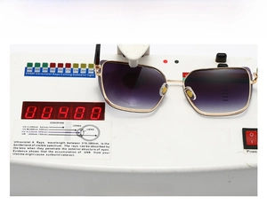 Detail showing square metal sunglasses on UV400 testing device with purple gradient lens