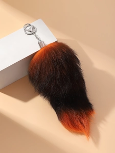 Close-up of oversized fluffy fox tail keychain with orange black gradient and silver clasp