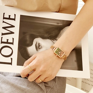 Elegant gold square watch with forest green dial and milanese mesh band on woman's wrist