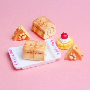 Miniature cat-themed Swiss rolls and cakes displayed on a soft pink background