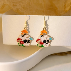Detail of gothic earrings with skull and colorful mushroom motifs on a display box