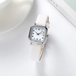 Montre quartz carrée argentée pour femme avec bracelet en cuir blanc sur un bureau