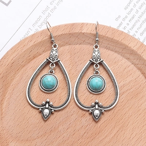 Detail shot of bohemian antique silver teardrop earrings with turquoise beads on wood