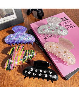 Flat lay of five star and moon hair claws in various glitter colors and rainbow patterns