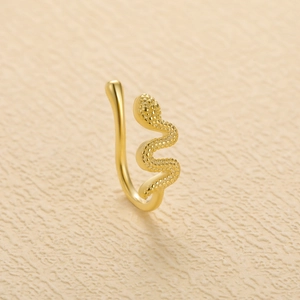Elegant gold S-shaped snake nose ring with detailed scale texture on beige background