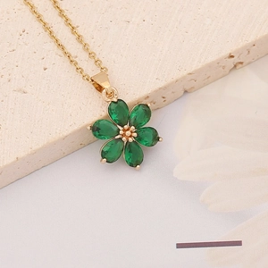 Close-up of emerald green zircon flower pendant with golden petals on a stone base