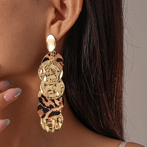 Detail of layered gold disk earrings with leopard print and hammered metal texture