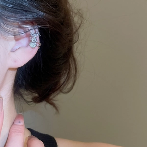 Detail view of silver ear cuff with zircon heart pendant and crown design on female ear