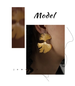 Detailed close-up of golden ginkgo leaf earrings with fine radial metal texture