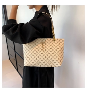 Dettaglio borsa tote crema con motivi geometrici, catena dorata e ciondolo a cervo