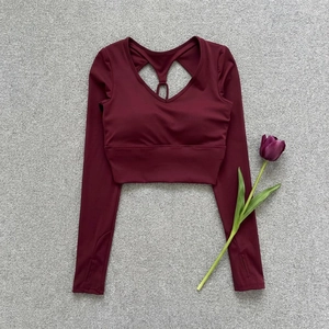 Detail of burgundy yoga crop top featuring back cutout with ring and thumbhole cuffs